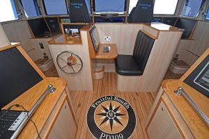A customised compass rose is incorporated into the wheelhouse floor, between the trawl console and the central desk area.