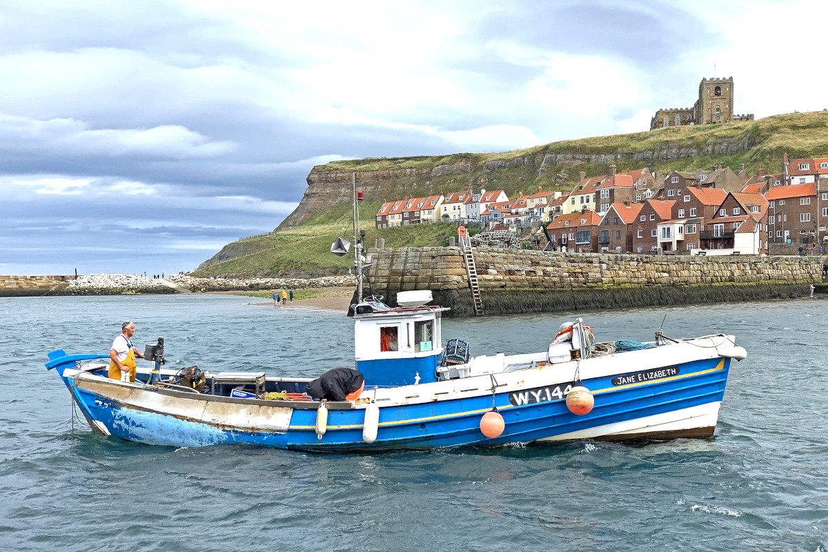 Jane Elizabeth returning to Whitby after hauling pots, with the historic St Hilda’s church dominating the skyline above the traditional red-roofed houses on Whitby’s Eastside. (Mick Bayes)