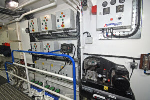 Electrical switchboards and box coolers are arranged across the fore end of the engineroom.